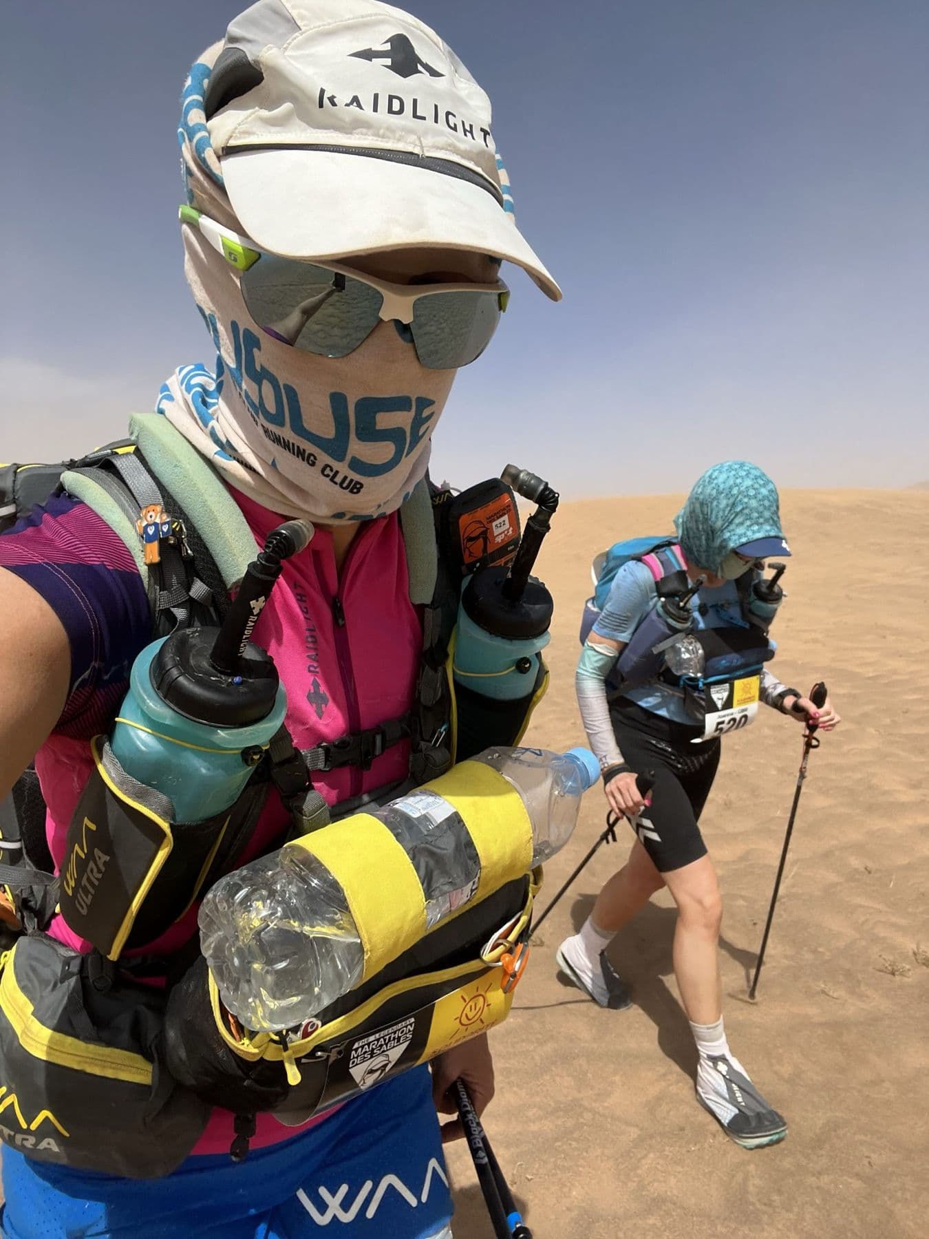Charlotte and a fellow runner trekking through blowing sand with faces covered
