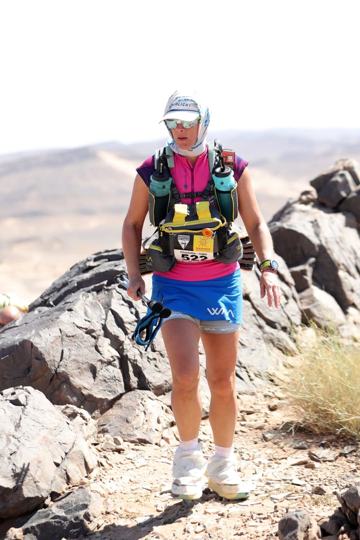 Charlotte climbing a rocky jebel with poles on the MdS mountain stage