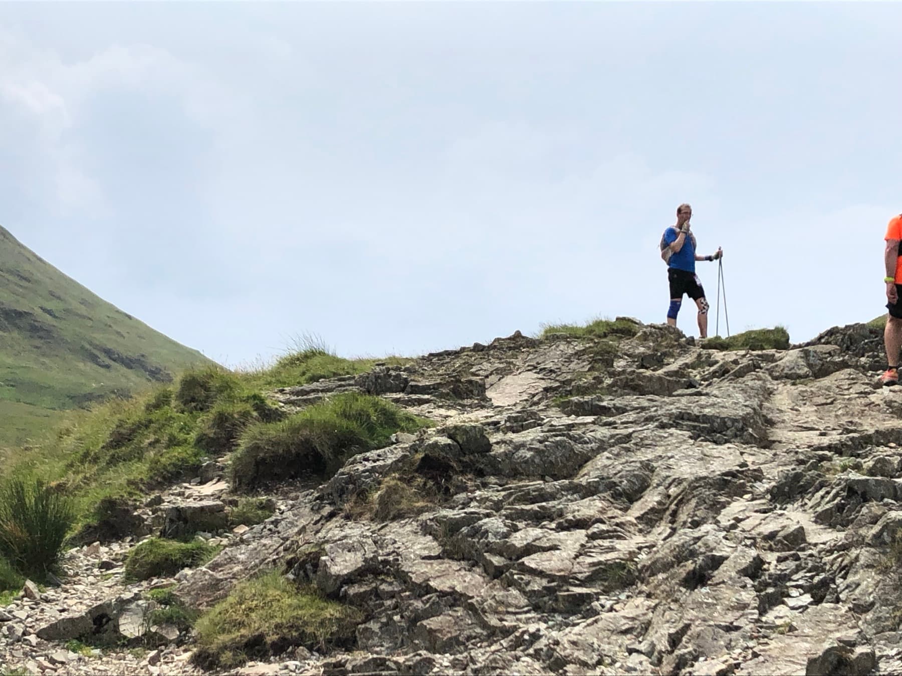Scott with poles on a rocky summit at the highest point of the day