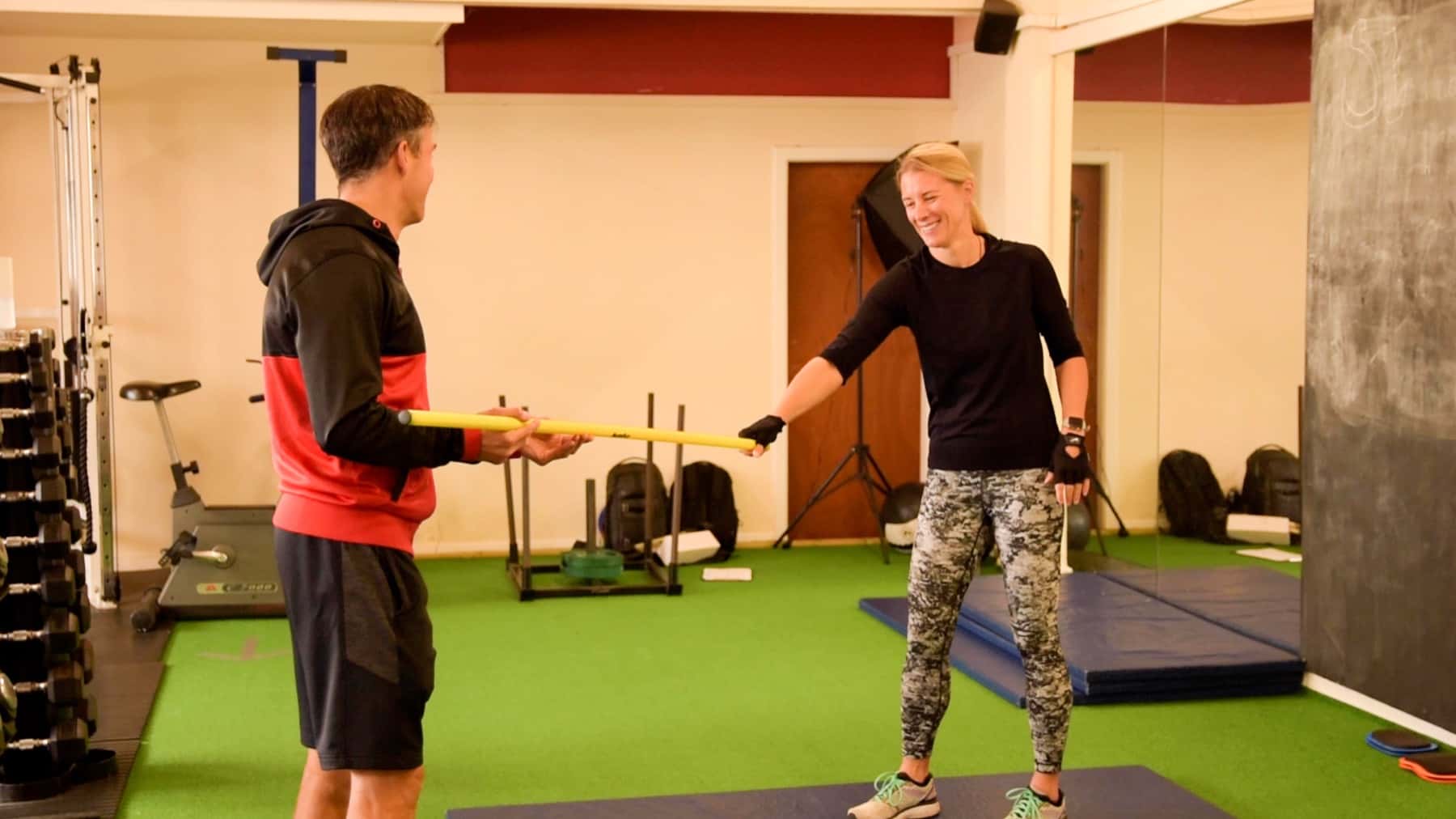 Trainer coaching a client with a dowel on the turf at Studio 121 in Nantwich